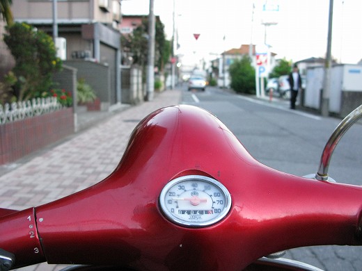 黄色い建物の前に立つライダーと白いベスパPX100E、納車時の記念写真のような一枚。