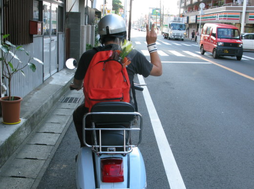 花束を背負ってVespaに乗るライダーの後ろ姿