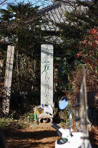 天狗塚を示す石碑とその前に止められたベスパの一部