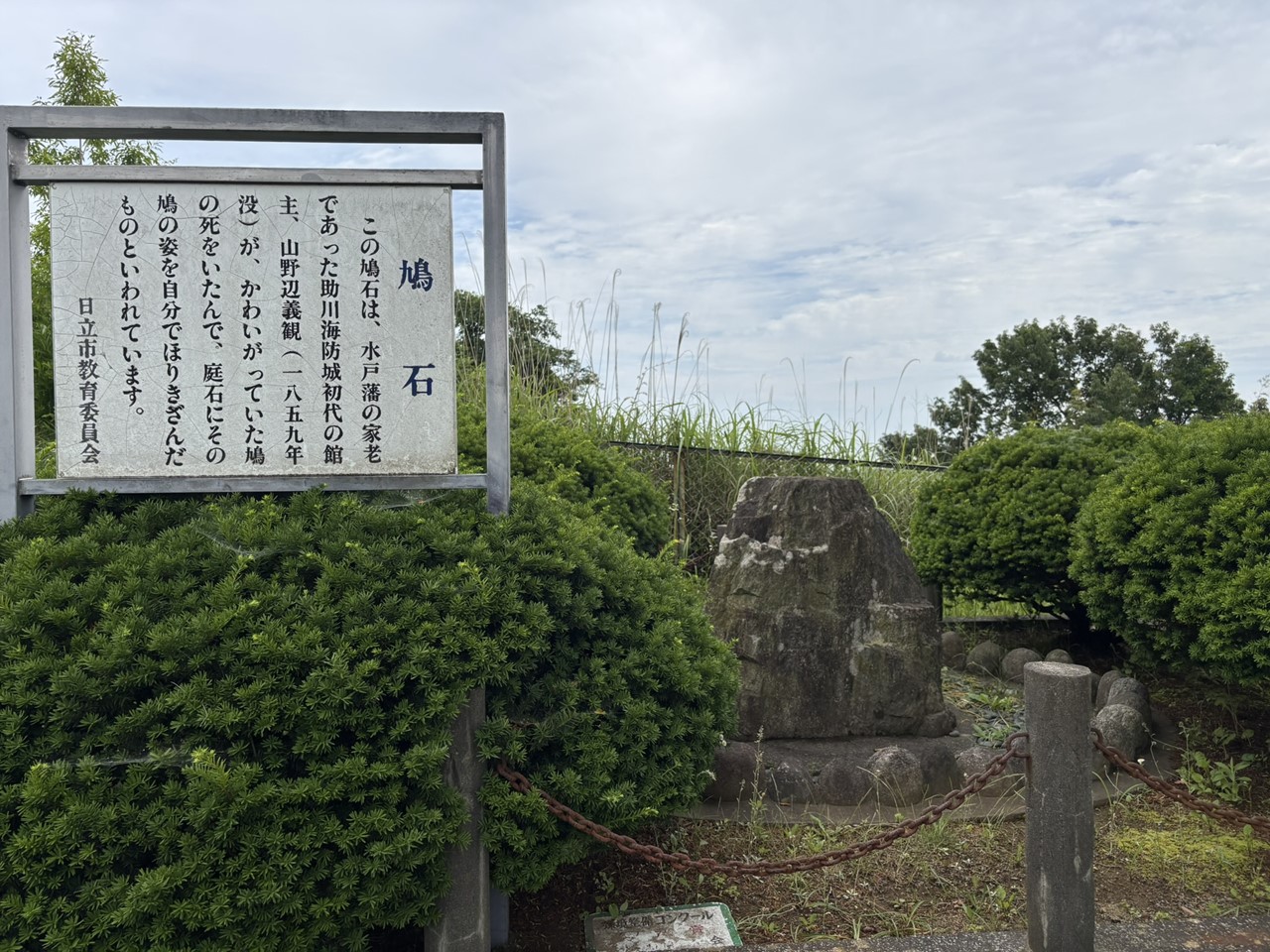 助川海防城跡にある鳩石とその由来を説明する案内板。