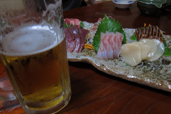 地元の居酒屋で刺身とビールを楽しむ夕食風景