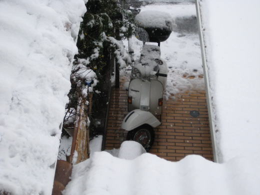 雪の中で静かに駐輪されたベスパP200Eの姿
