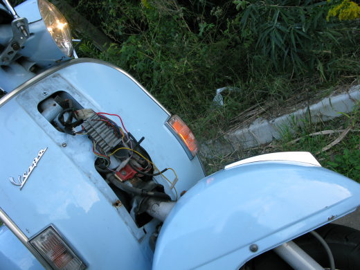 夜間にヘッドライトを点けて停車しているVespa PX200E