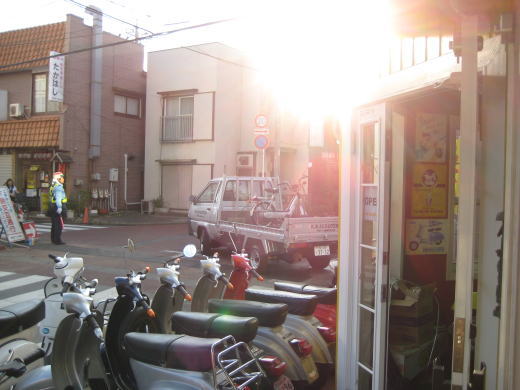夕日で逆光になったK.B.SCOOTERSの店舗前とトラックの風景