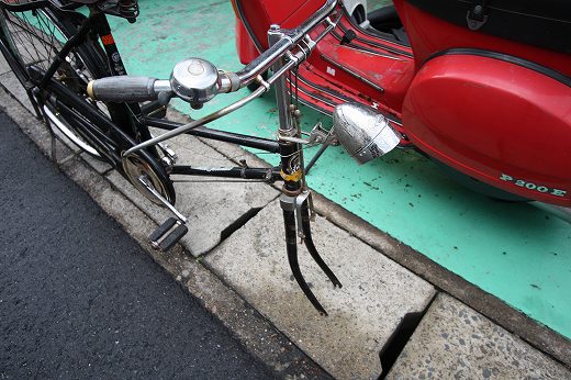 赤いベスパの横に停められた実用自転車のハンドルまわり。