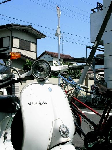 強い日差しで眩しく反射する白いベスパのボディー