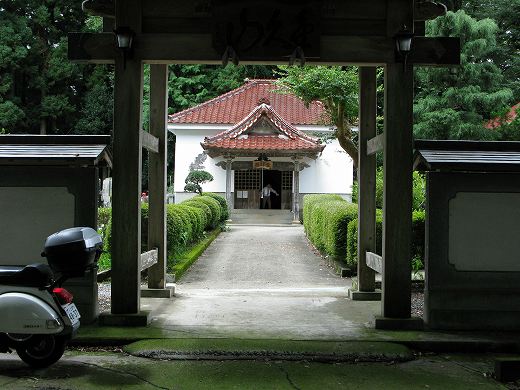 赤瓦の寺院を正面に望む構図。境内には白いベスパが佇んでいる。