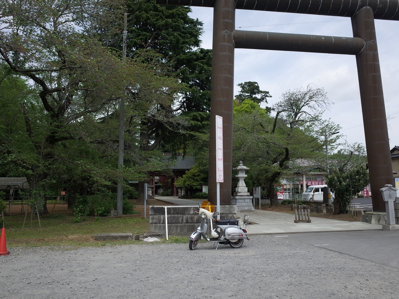 大宝八幡宮の巨大な鳥居の前に停めたベスパ。境内の木々が新緑に染まる。