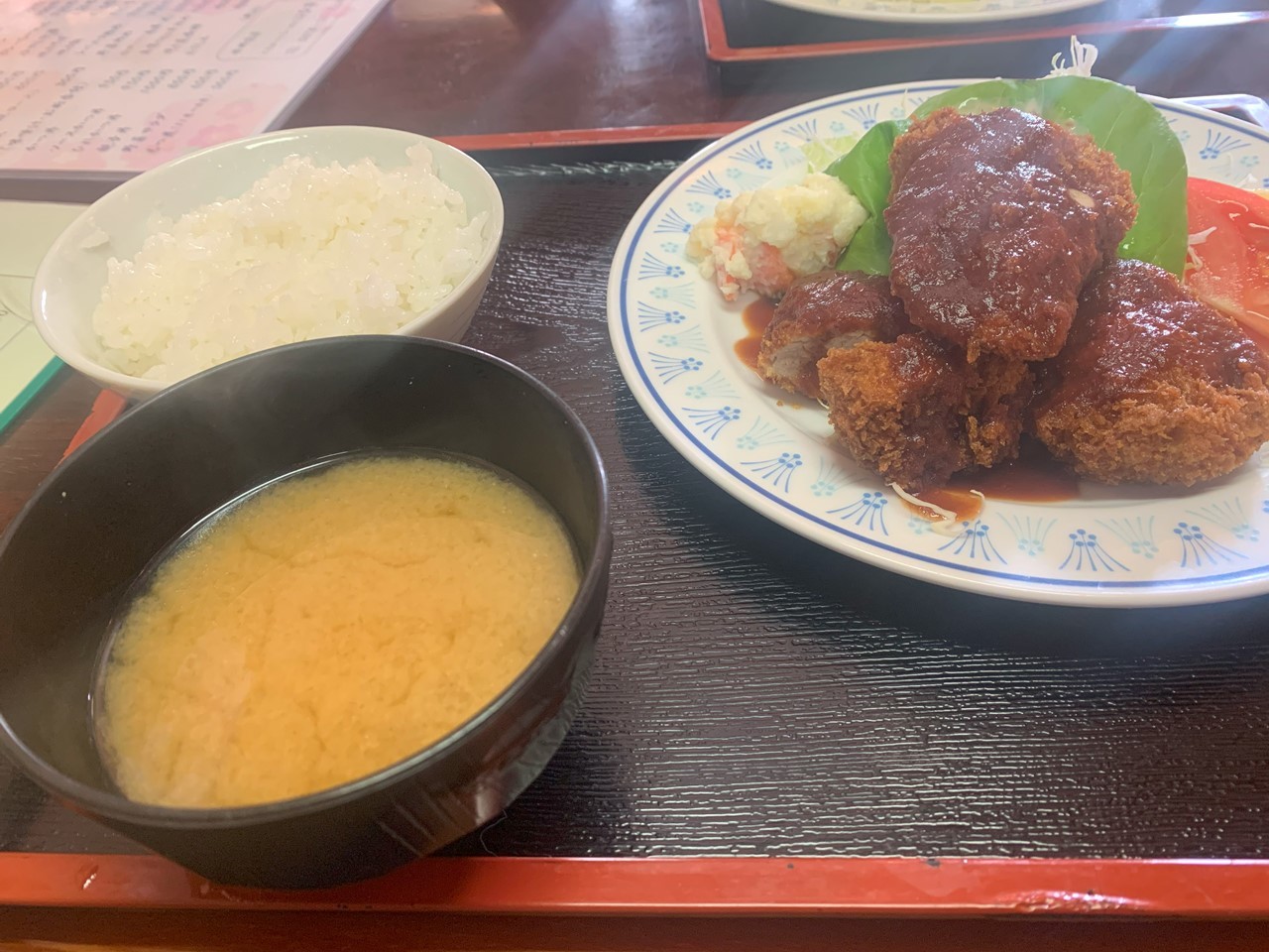 味噌汁・ご飯・キャベツ付きのソースとんかつ定食。湯気が立ちのぼる温かい一膳。