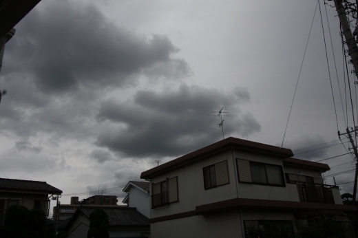 雨が降り出しそうな曇り空と住宅街の屋根