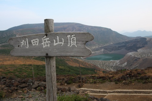 刈田岳山頂の木製標識と背景に広がる火口湖