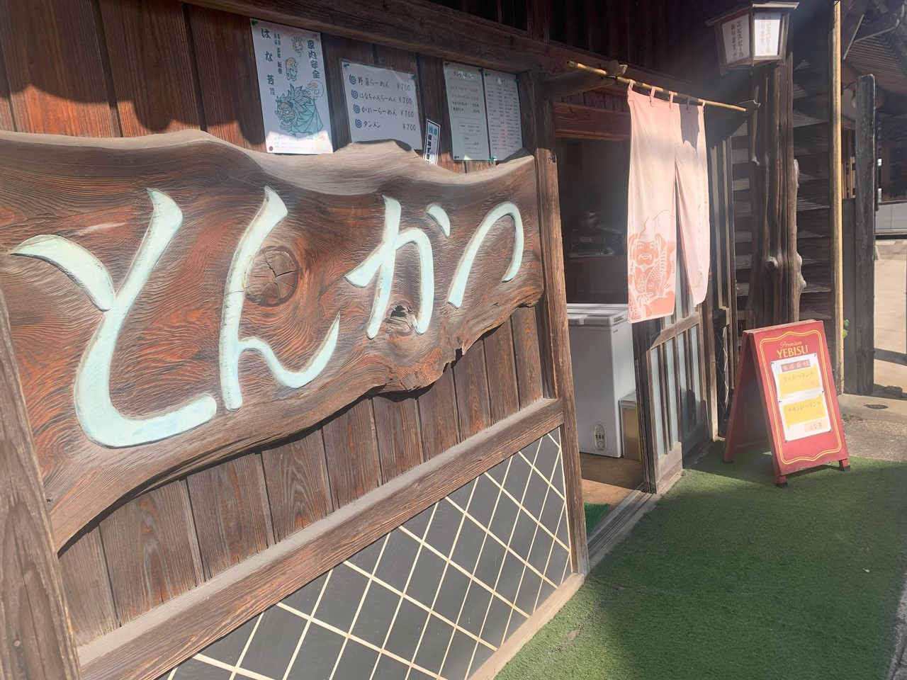 木製看板に「とんかつ」と描かれたレトロな外観の店。入口にのれんがかかっている。