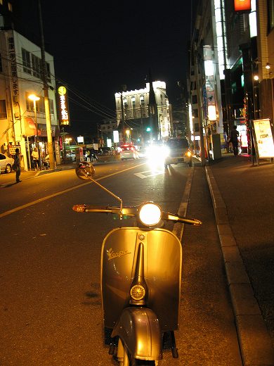 夜の街で試運転中のベスパのリアビュー