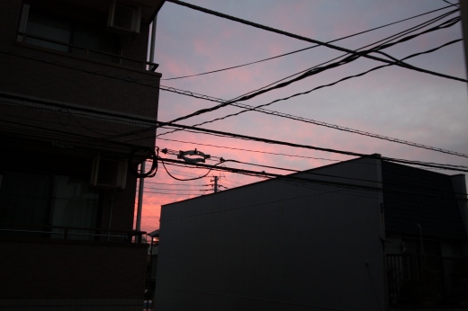 夕焼けに染まる空と電線、建物の影