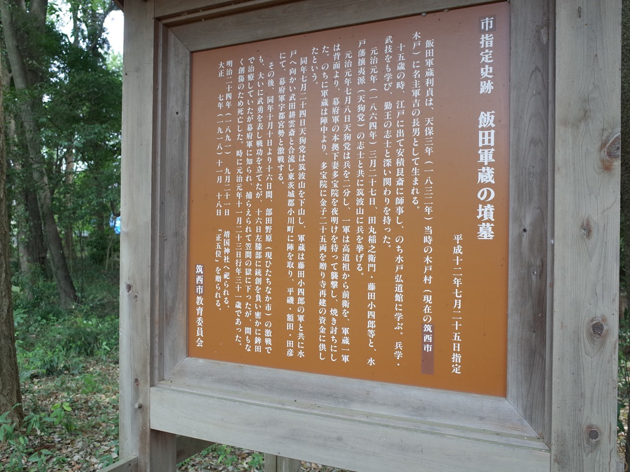 樹々に囲まれた静かな一角に建つ飯田軍蔵の墳墓と石碑。