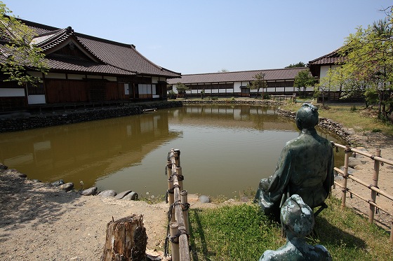 日新館にある日本最古のプールとされる堀を銅像越しに眺めた写真