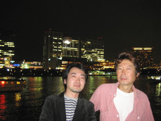 東京湾の夜景を背に記念写真に収まる男性二人の姿