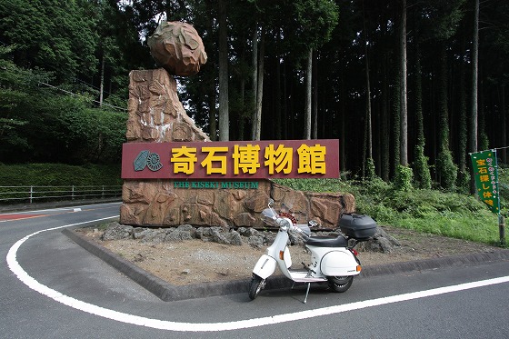 奇石博物館の大きな看板前に停めた白いベスパ。