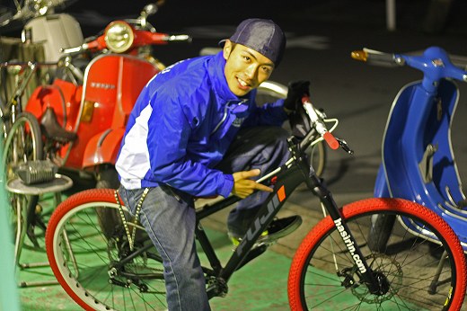 藤井君がBMXに乗ってポーズ、背景にベスパが並ぶ