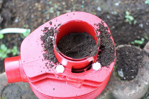 小石の上から土を入れた植え込み作業途中のシリンダー