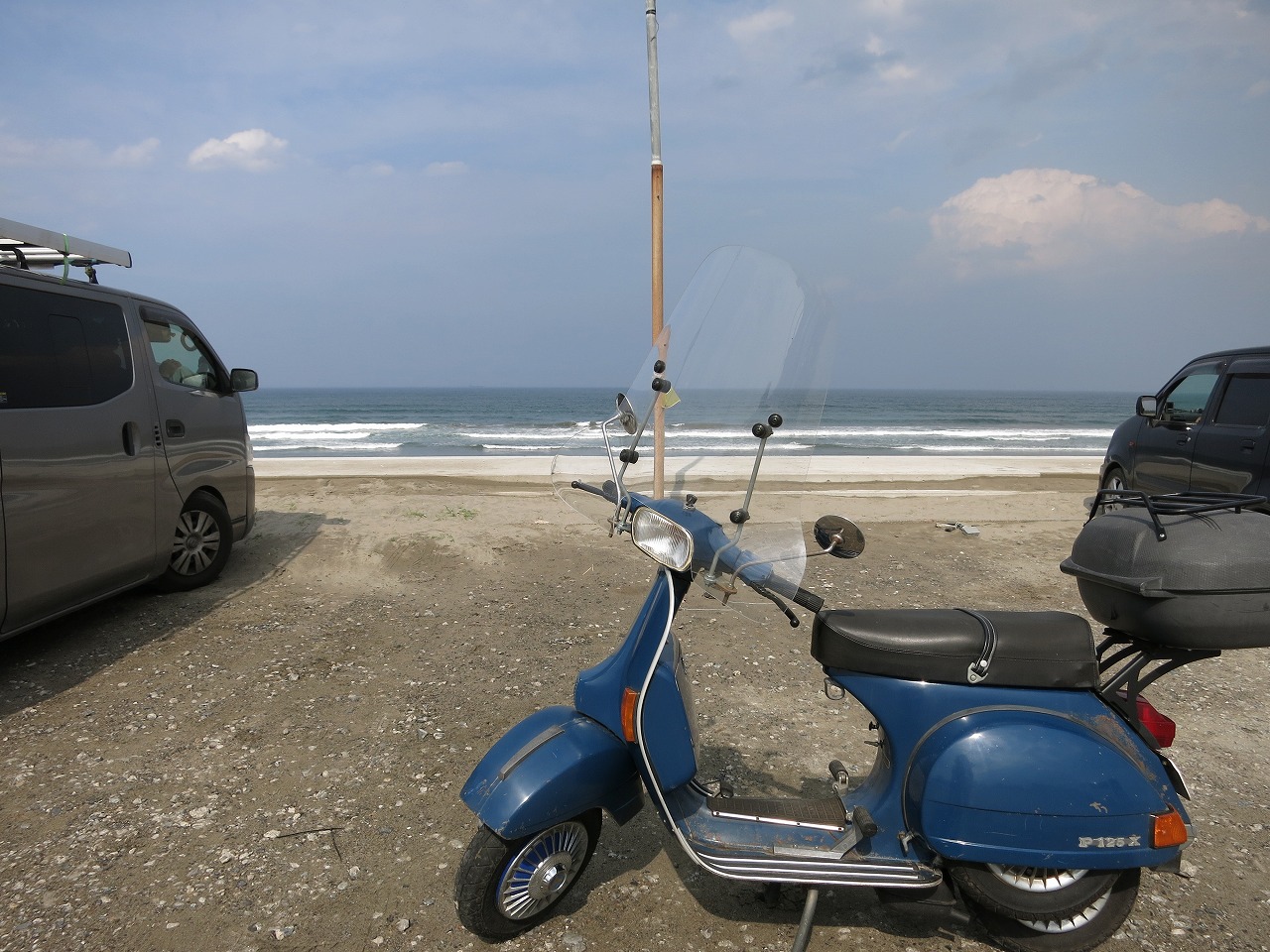 広々とした海岸と防波堤、遠くに風車が見える景色