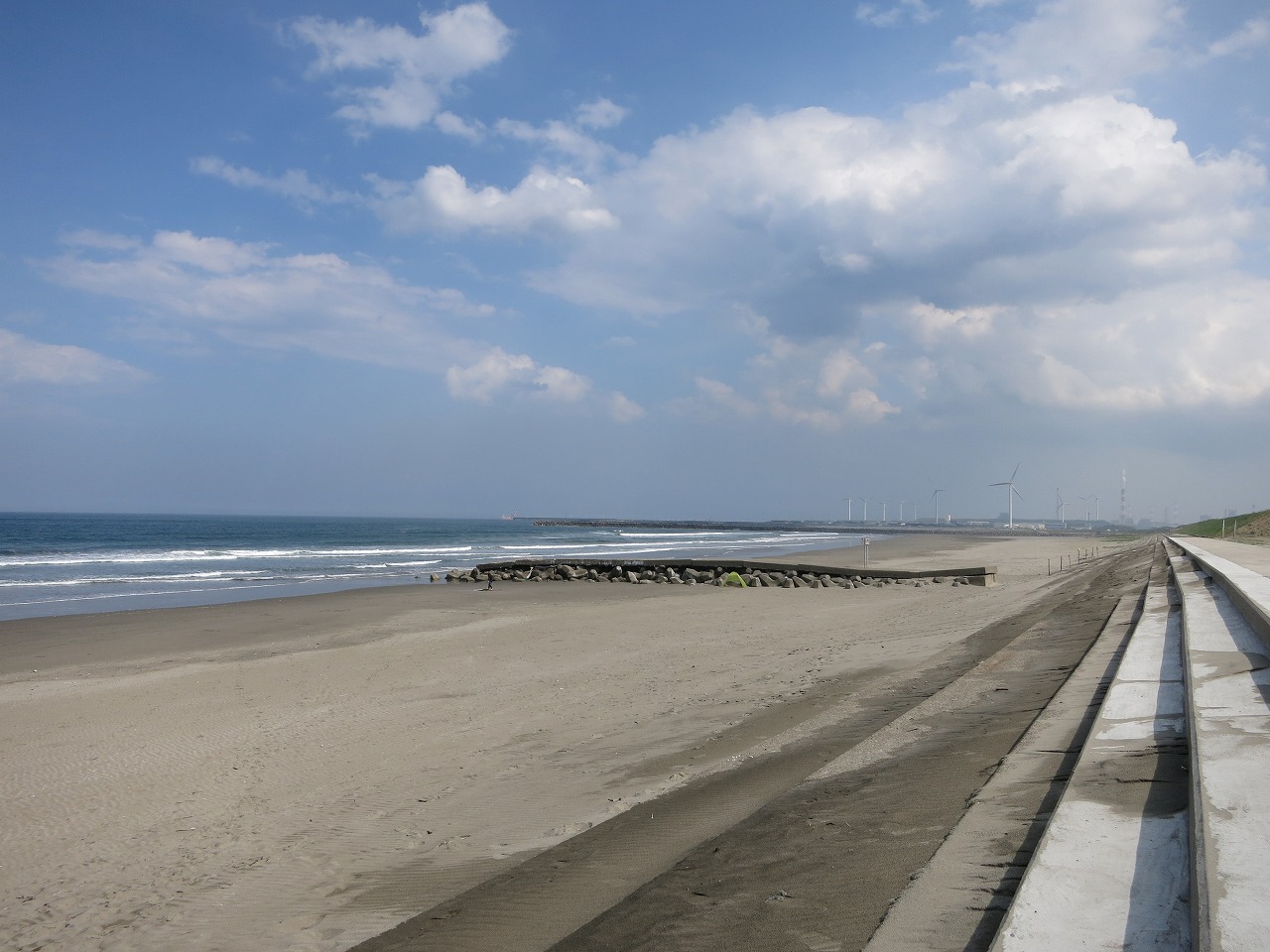 海辺に停車中の青いベスパと波打ち際の風景