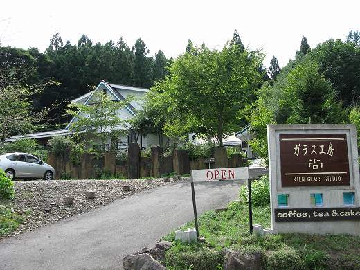 「ガラス工房 尚」の店舗と周囲の木々に囲まれた静かな道
