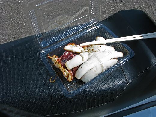 ベスパのシート上に置かれた冷たい焼きイカ弁当