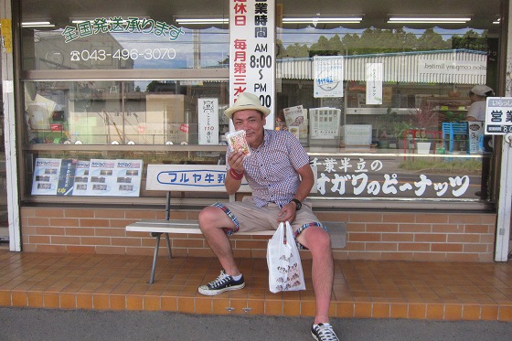 オガワのピーナッツ店前で商品を持って満面の笑み