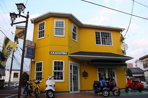 黄色い外壁のK.B.SCOOTERS店舗の外観