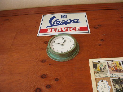 壁に掛かった時計とVespa SERVICEの看板