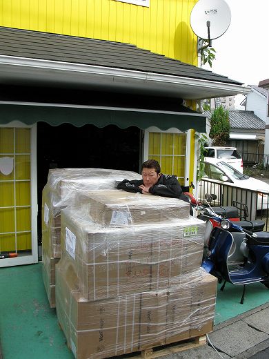 パーツの入った荷物に寄りかかるスタッフとVespa