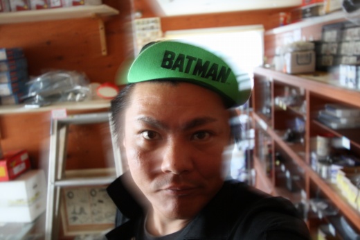 BATMANのサイクルキャップを被って笑みを浮かべる男性のセルフィー。