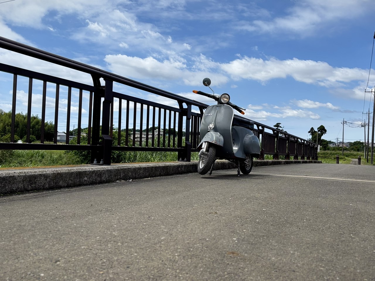 青空の下、橋の上に停車したベスパ50Rの横向き写真