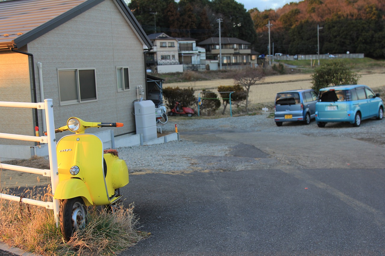 敷地入口に置かれた目印の黄色いベスパと建物の外観