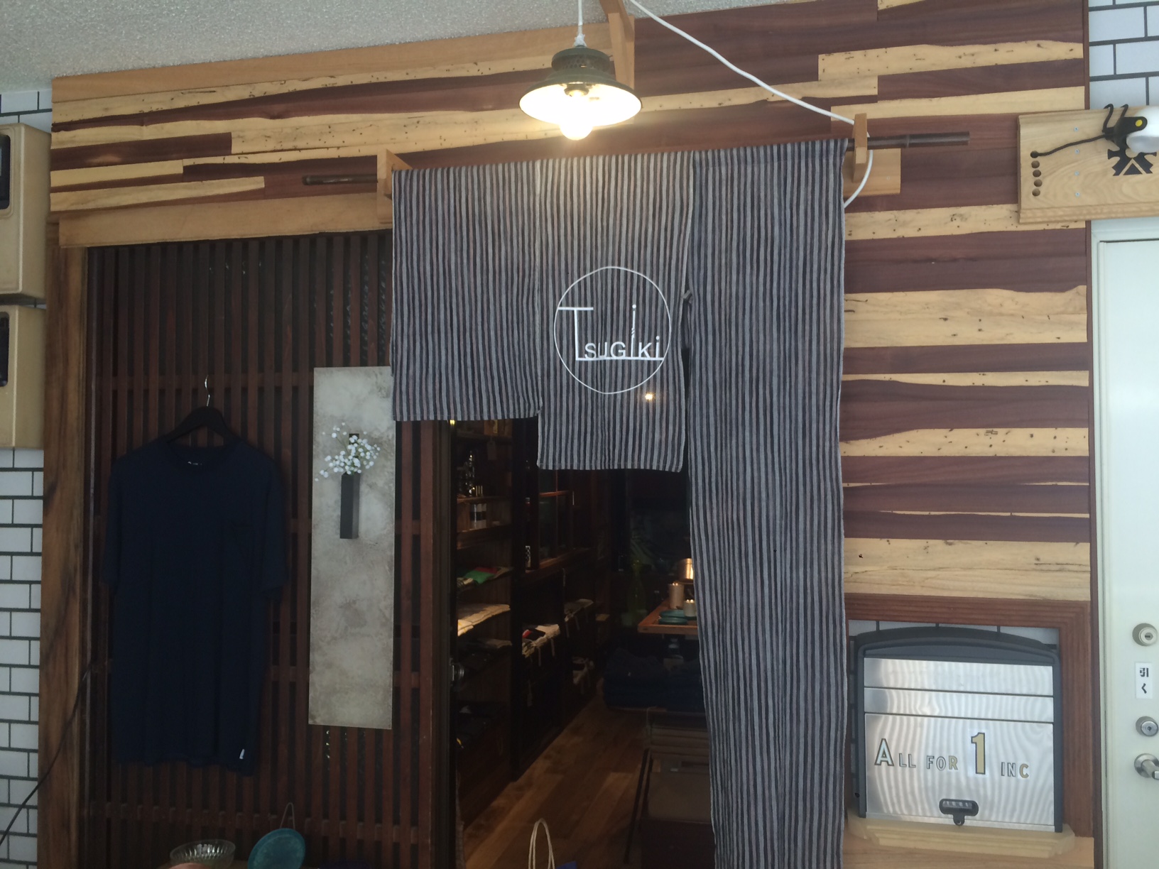 TSUGIKIの外観、白い暖簾と木の扉が印象的な店舗前景