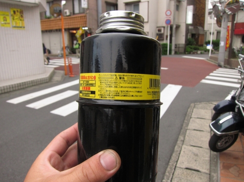 タオルに包まれたガソリン携行缶をジャッキ代わりに使っているベスパ修理の現場。