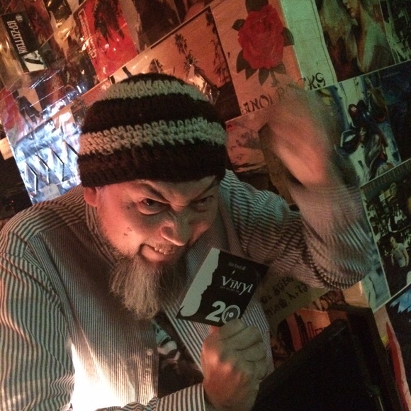 ROCK & SOUL BAR Vinylの店内で笑顔のマスターが20周年ステッカーを手にしている様子