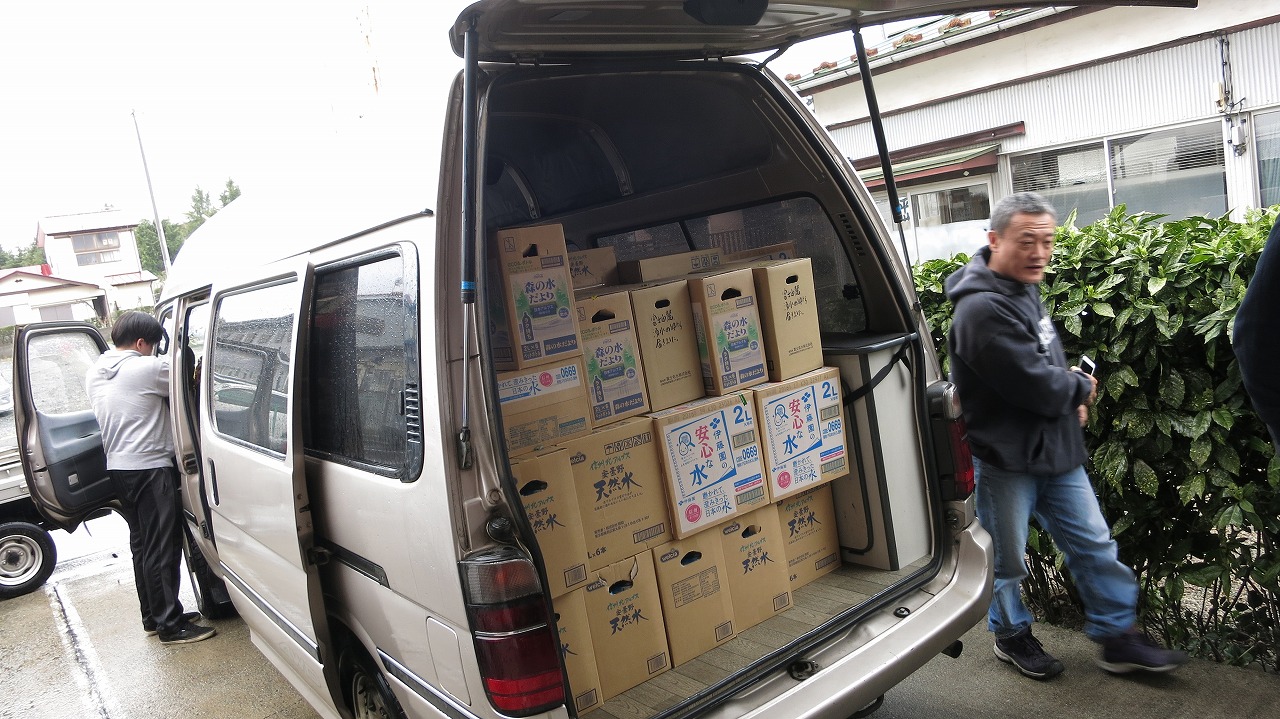 保育園前でミネラルウォーターを届ける一行