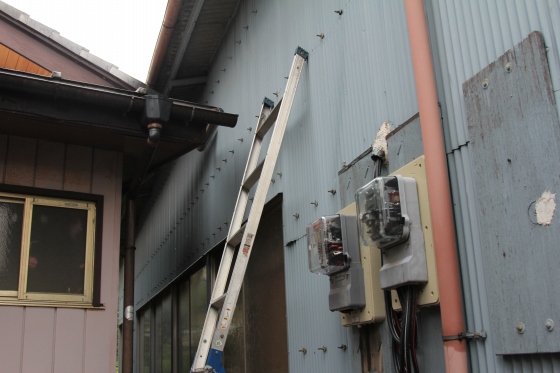 雨の合間を縫って雨樋の点検をしている場面