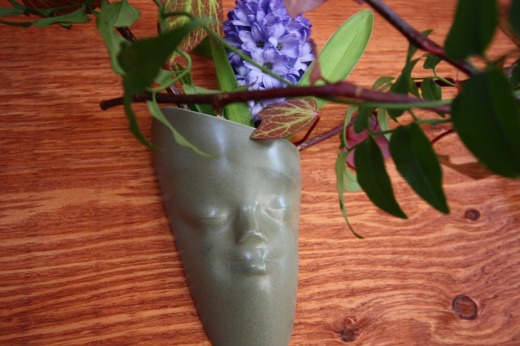 顔の形をした一輪挿しに活けられた紫の花
