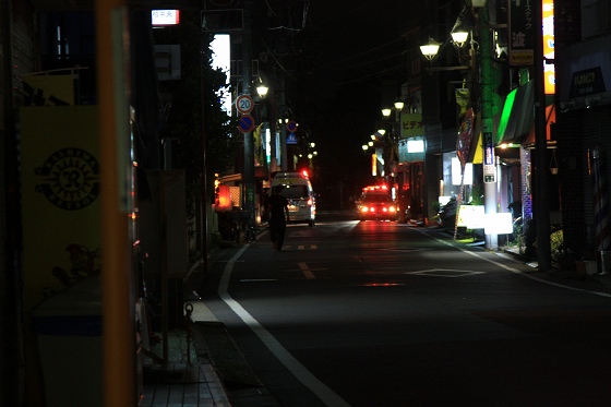 夜の通りで対応中のパトカーと救急車の様子