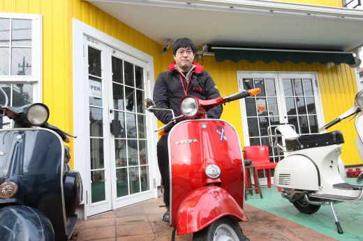 店頭で赤いベスパにまたがる男性の納車記念ショット