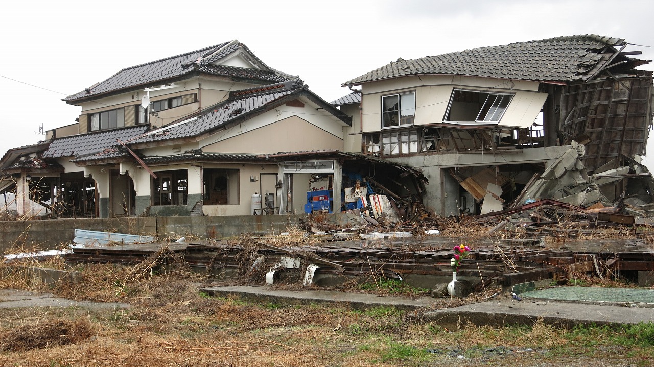 被災した家屋の壁と倒壊した屋根