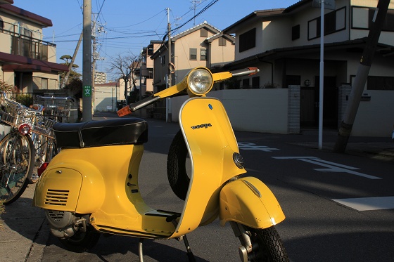 オリジナルペイントの黄色いVespa50Rを店の奥から引き出したシーン