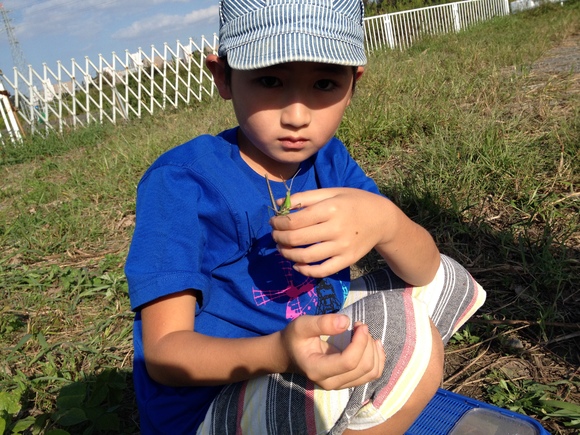 大きなバッタを捕まえて満足げな子ども