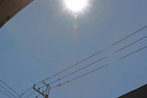 強烈な日差しが照りつける真夏の青空と電線の風景