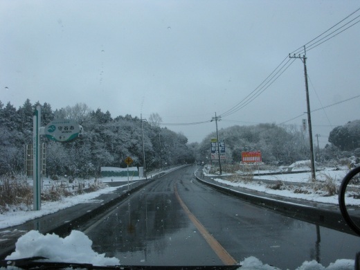 雪景色の中、濡れた道路を進む車の車窓からの眺め