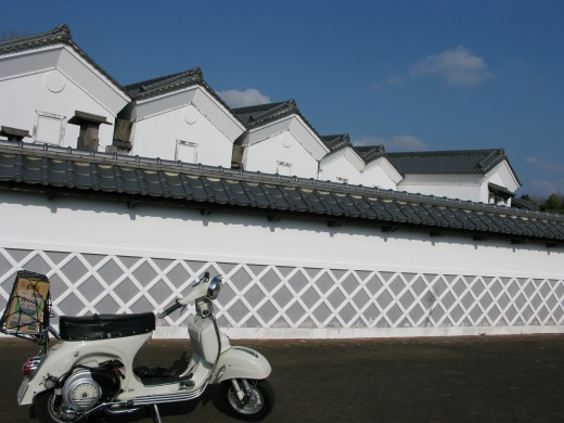 白壁の建物とベスパが並ぶ、和風の町並み風景