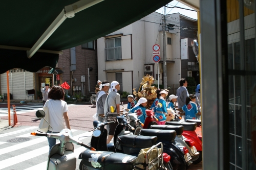 店の前で元気に御神輿を担ぐ近所の子供たちの様子